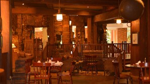 Un accogliente ristorante con arredi in legno, pareti in pietra e luci a sospensione.