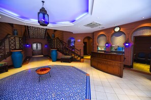 A lobby with a blue patterned floor, a staircase, and a reception desk. - Kampala Serena Hotel (Kampala)