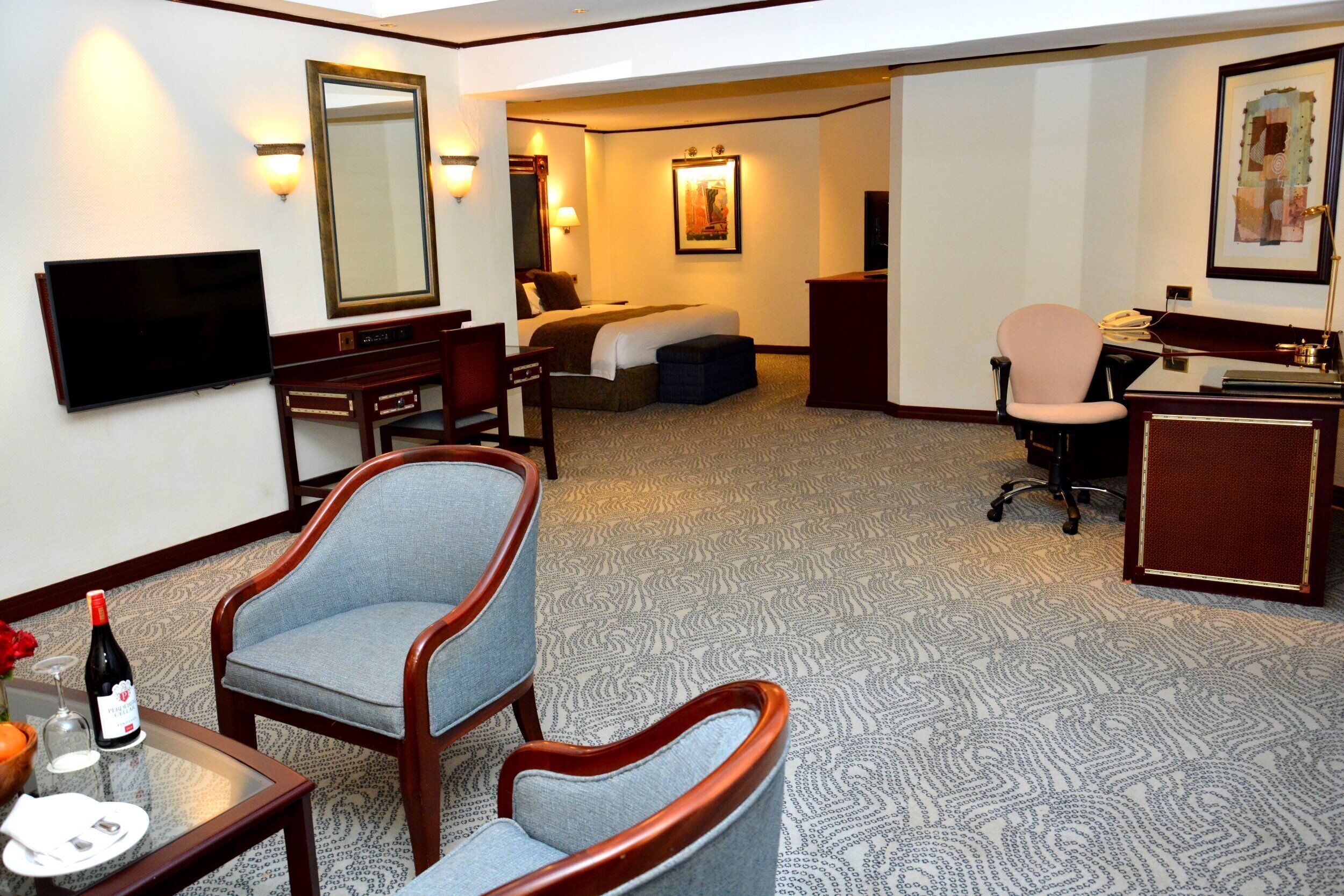 Une chambre d’hôtel équipée d’un lit, d’un bureau, d’une chaise, d’une télévision et d’une lampe de bureau.