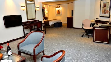 A hotel room with a bed, a desk, a chair, a television, and a desk lamp.