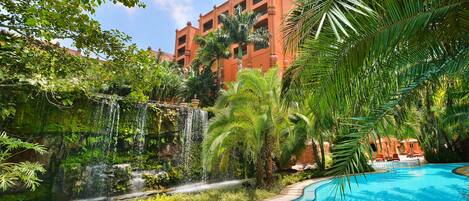 Una piscina al aire libre, sombrillas, sillones reclinables de piscina