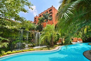 Una piscina al aire libre, sombrillas, sillones reclinables de piscina