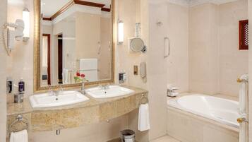 A hotel bathroom with two sinks, a large mirror, a bathtub, and a shower.