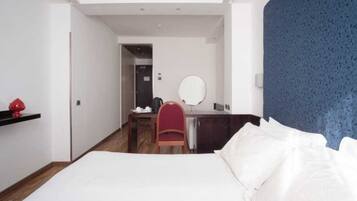Ein Hotelzimmer mit Bett, Schreibtisch, Stuhl, Spiegel und einem roten dekorativen Element an der Wand.