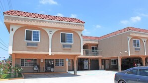 A two-story building with a red-tiled roof, a covered parking area, and a single-story annex. - Orange Tustin Inn (Orange)
