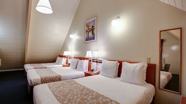A hotel room with three beds, a large mirror, and a painting on the wall. - Newport Channel Inn - Near Huntington State Beach (Newport Beach)