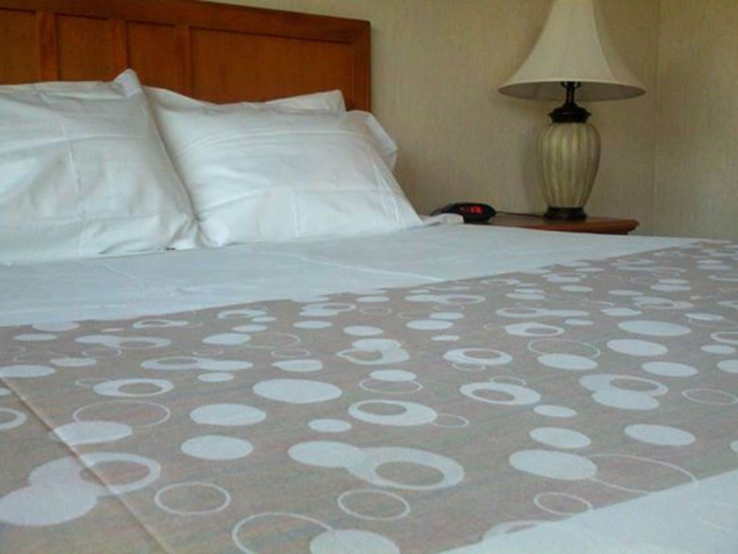 Una cama bien hecha con ropa de cama blanca y una manta estampada.