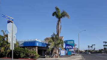 A hotel with a blue facade, palm trees, and a clear blue sky.