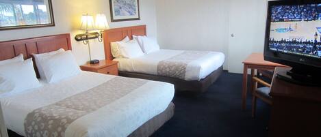 A hotel room with two beds, a television, and a desk.