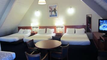 A hotel room with two beds, a dining table, chairs, a TV, and a painting on the wall.