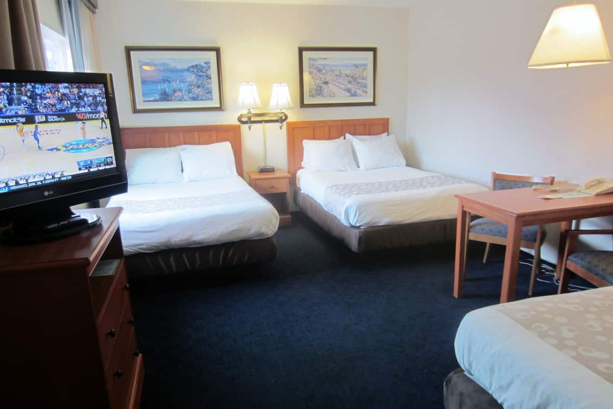 A hotel room with two beds, a desk, a television, and two wall-mounted lamps.