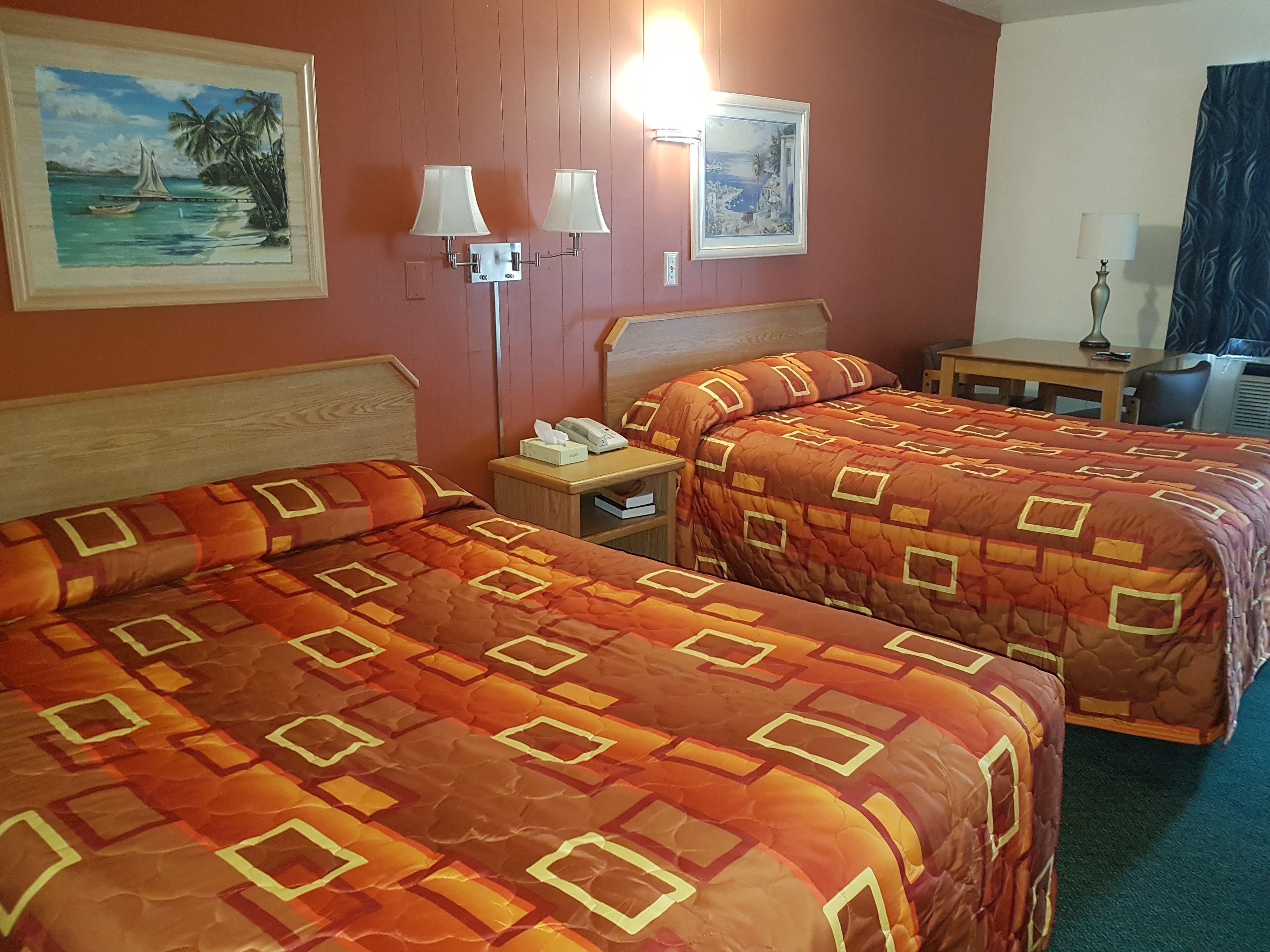 Une chambre d’hôtel avec deux lits, une table de chevet, un bureau et deux lampes fixées au mur.