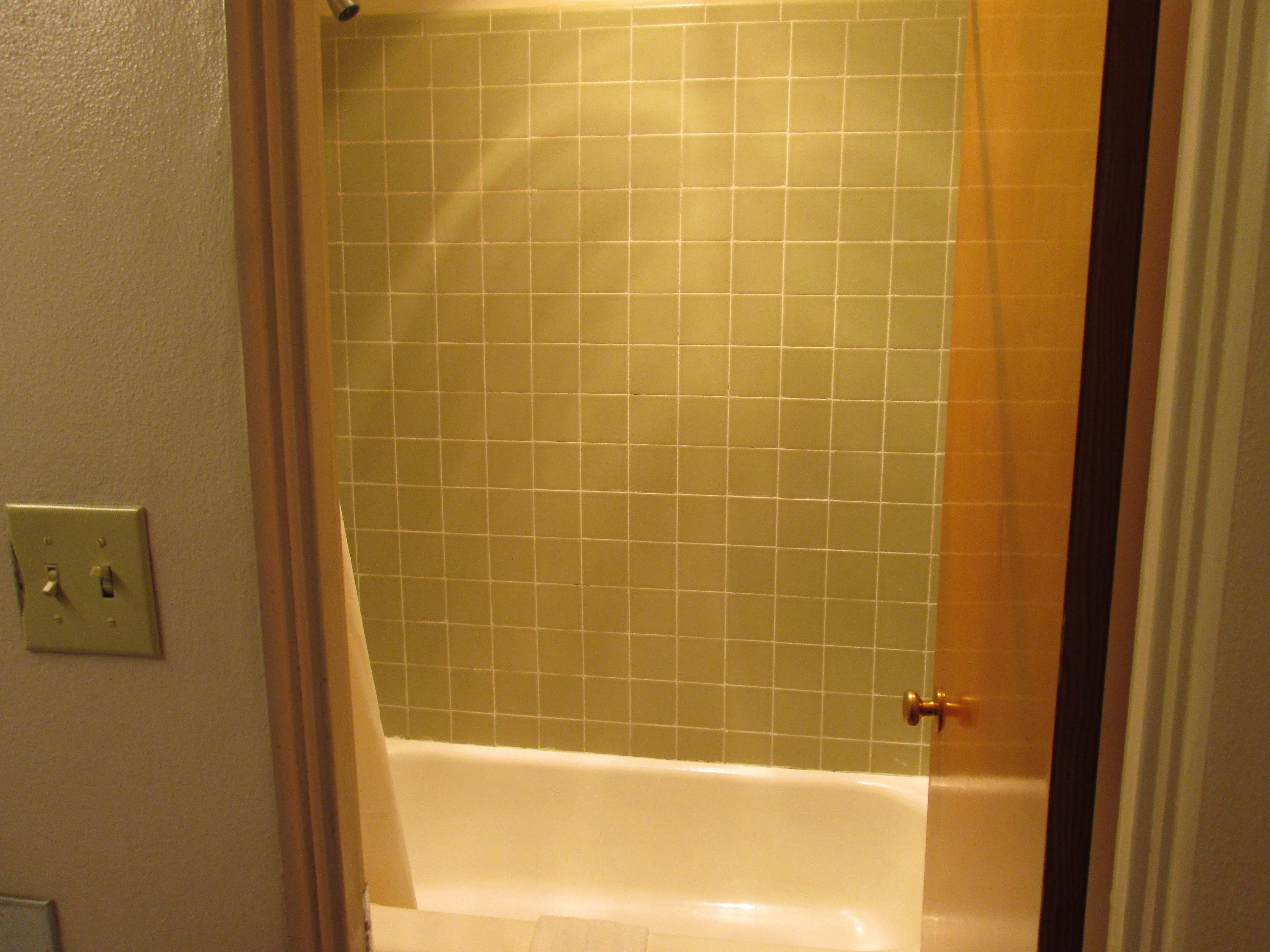Un baño con bañera, paredes de azulejos y una puerta.