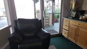 Uma cadeira de couro preto num quarto com um armário de madeira e uma máquina de café.