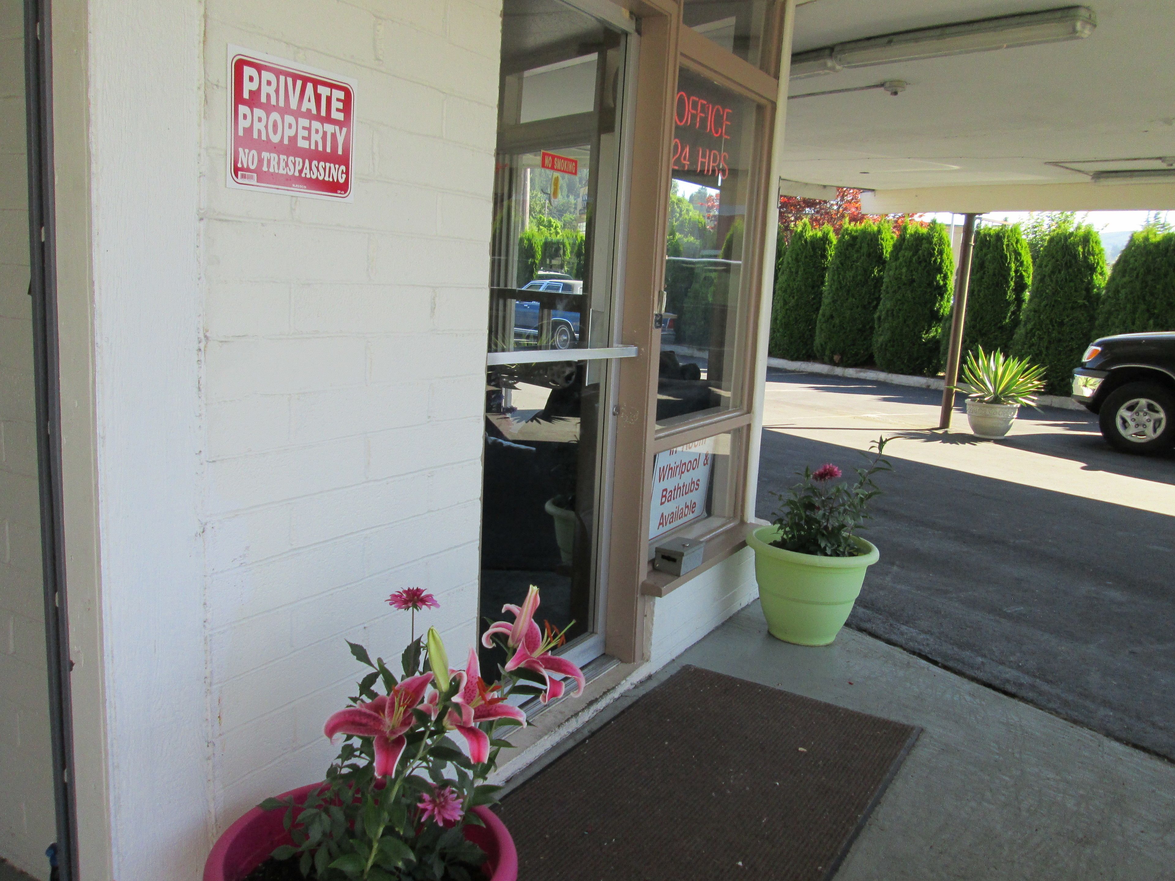 A private property with a 'No Trespassing' sign, a '24 HRS Office' sign, and a sign for 'Whirlpool & Bathtubs Available'.