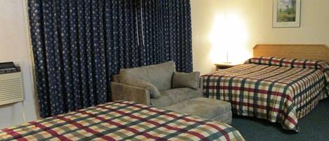 A hotel room with two beds, a sofa, a lamp, and a painting on the wall.