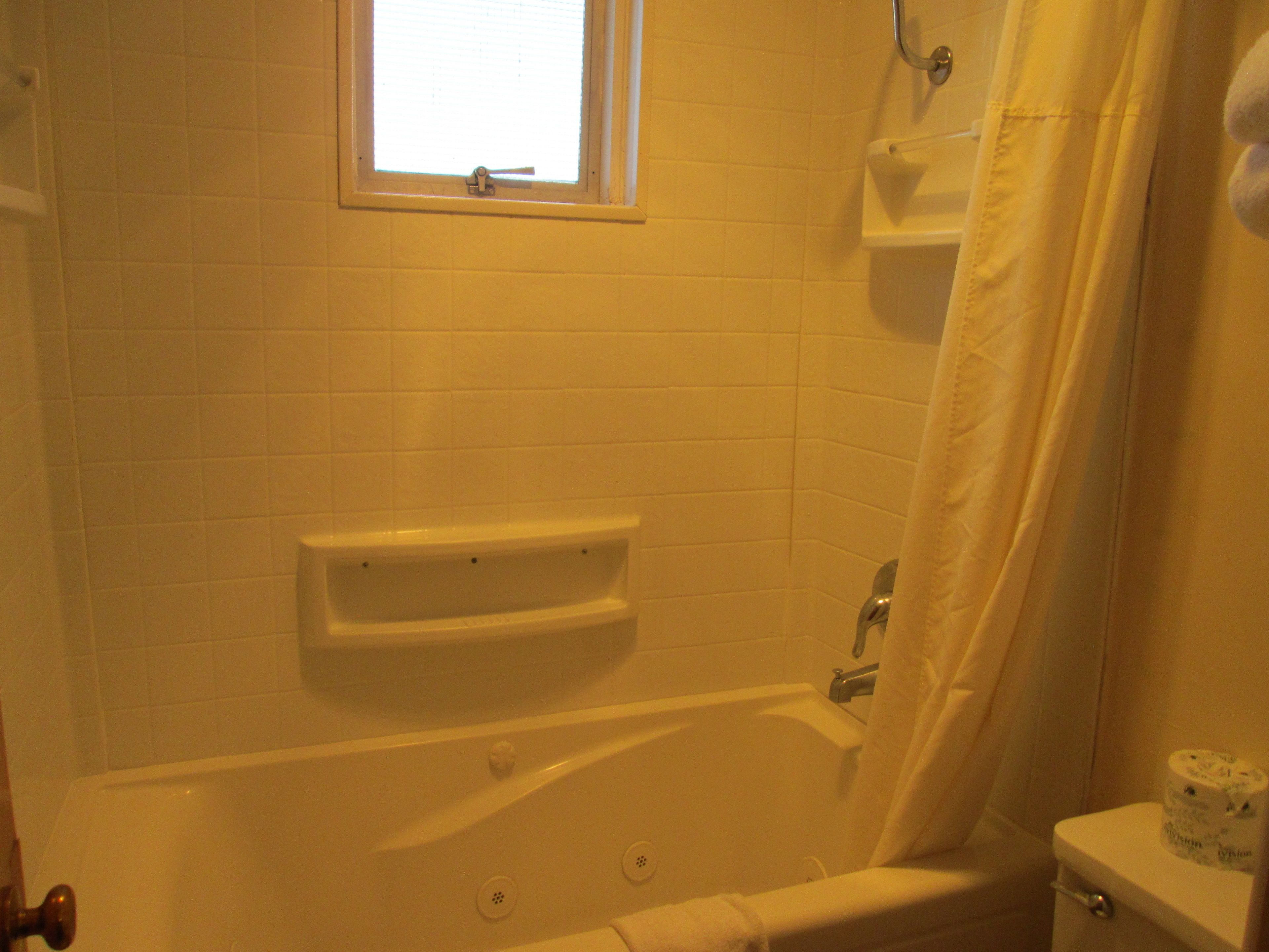 Ein Badezimmer mit Badewanne, Fenster und Toilette.