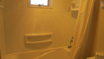 Ein Badezimmer mit Badewanne, Fenster und Toilette.