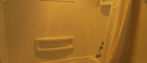 A bathroom with a bathtub, a window, and a toilet.