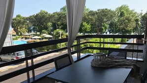A balcony with a table and chairs, overlooking a parking area and a pool. - Alexandra Stay Residence (Sirmione)
