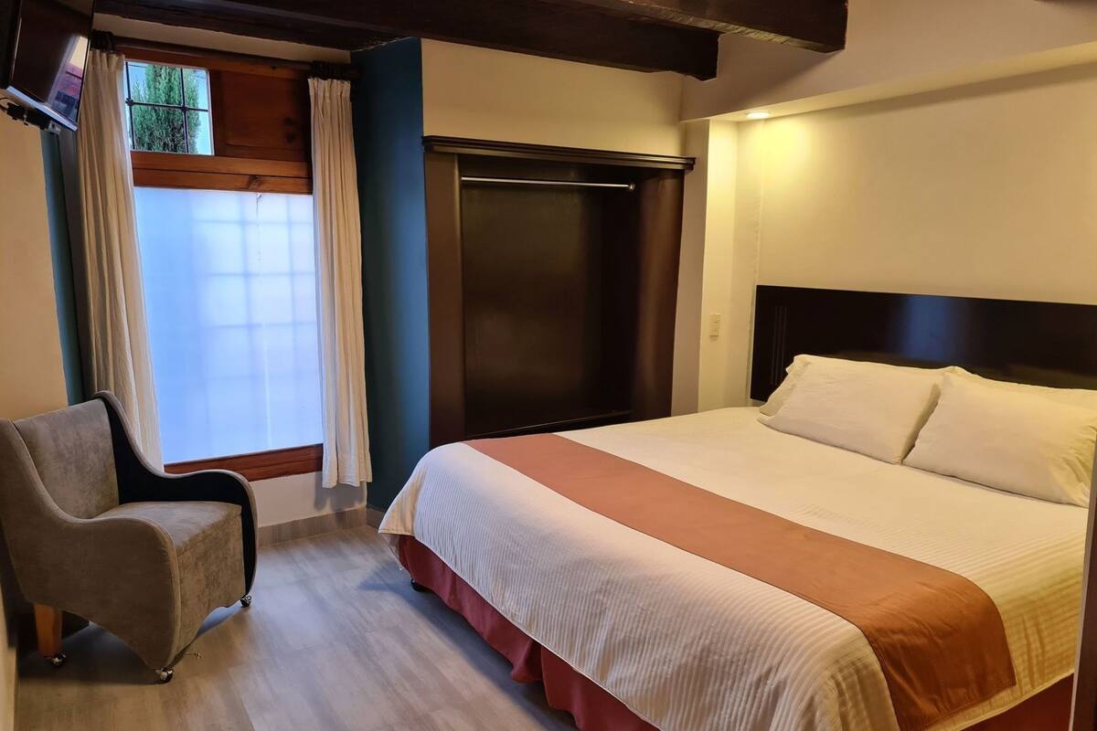 Ein Hotelzimmer mit Bett, Stuhl, Kleiderschrank und einem fensterbehangenen Fenster.