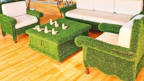 A cozy indoor seating area with a wooden ceiling, a white sofa, and green artificial grass furniture. - Hotel Barrio Antiguo (San Cristóbal de las Casas)