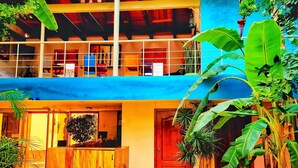 A multi-level building with a central courtyard, featuring a wooden reception desk, a red door, and a blue awning. - Hotel Barrio Antiguo (San Cristóbal de las Casas)