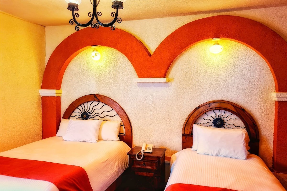 Ein Hotelzimmer mit zwei Betten, einer Kristallleuchter und einem Telefon auf einem Nachttisch.