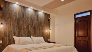 A bedroom with a wooden headboard, a large bed with white bedding, and a wooden door. - Hotel Barrio Antiguo (San Cristóbal de las Casas)