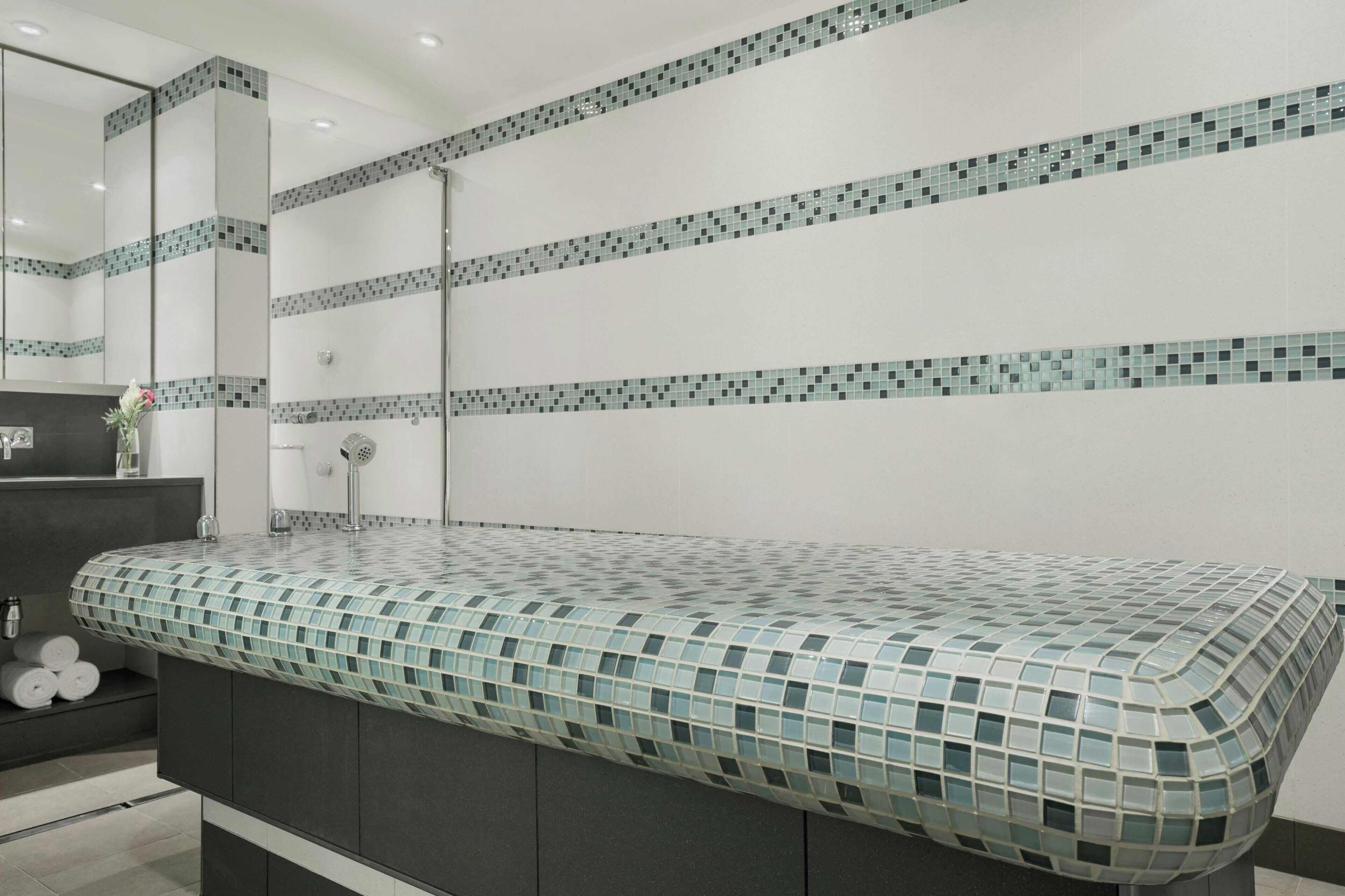 A modern bathroom with a tiled backsplash, a large mirror, and a built-in sink.