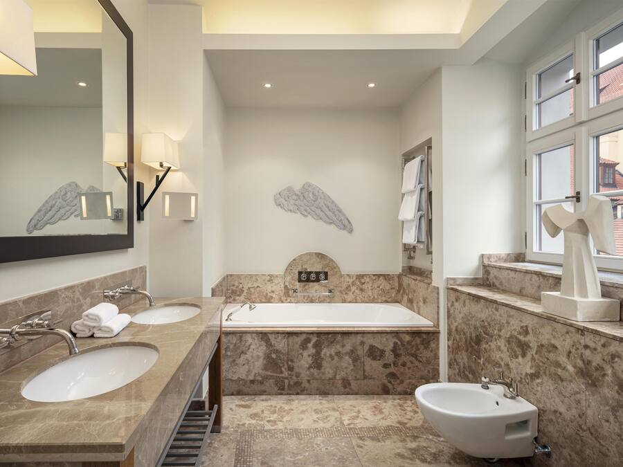 A modern bathroom with two sinks, a bathtub, a bidet, and a large mirror.