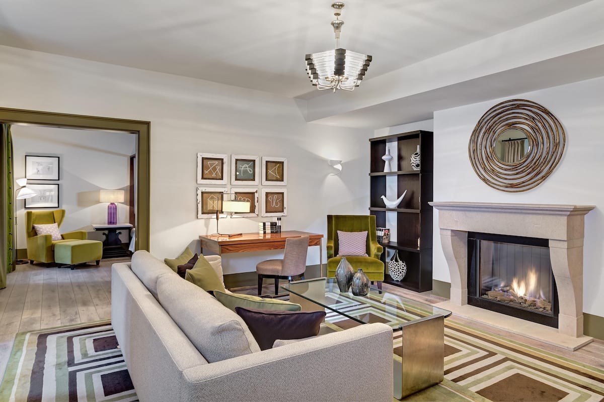 A modern living room with a fireplace, a chandelier, and a dining area with a wooden table and chairs.