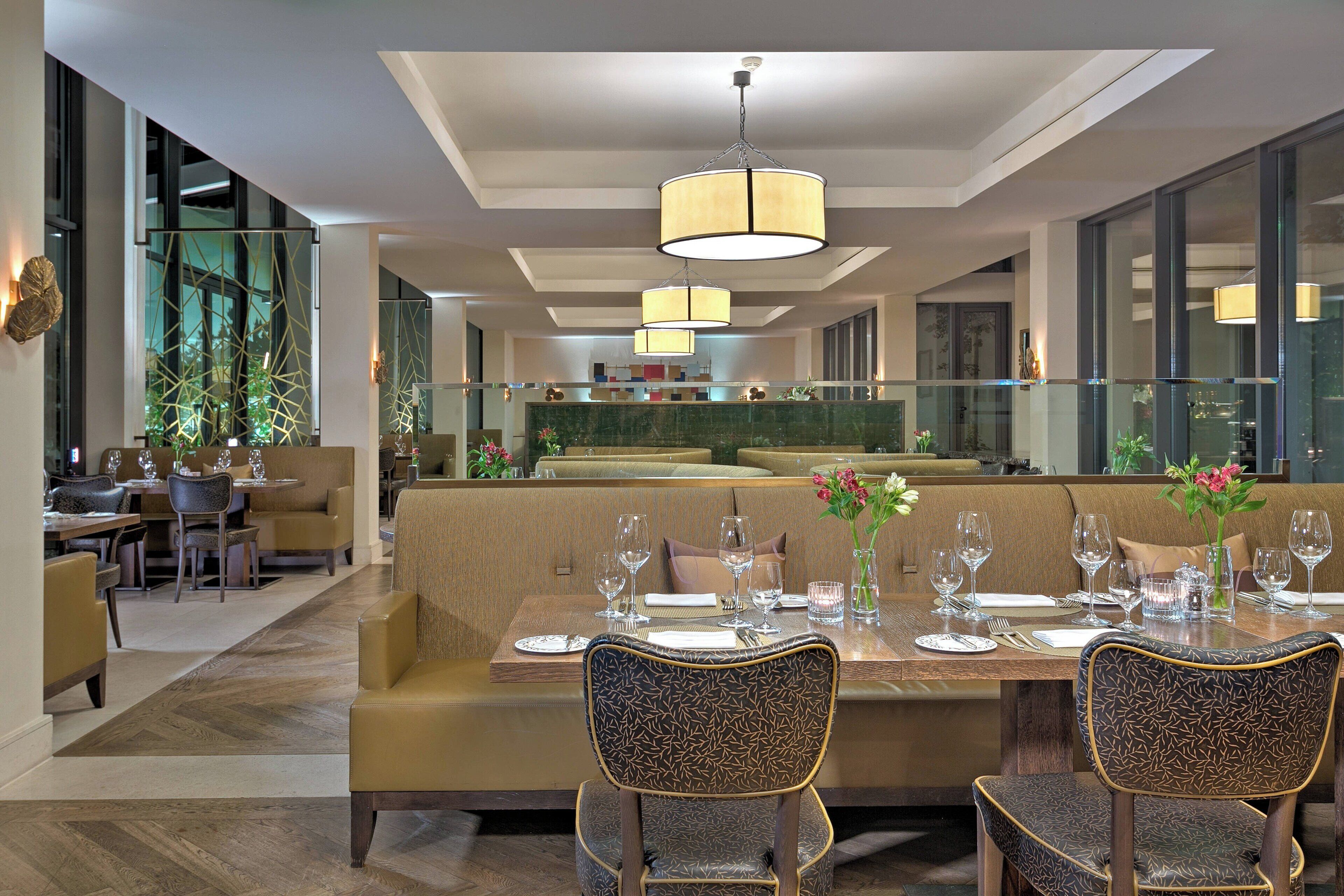 A modern dining area with a long table set for four, surrounded by cushioned seating.