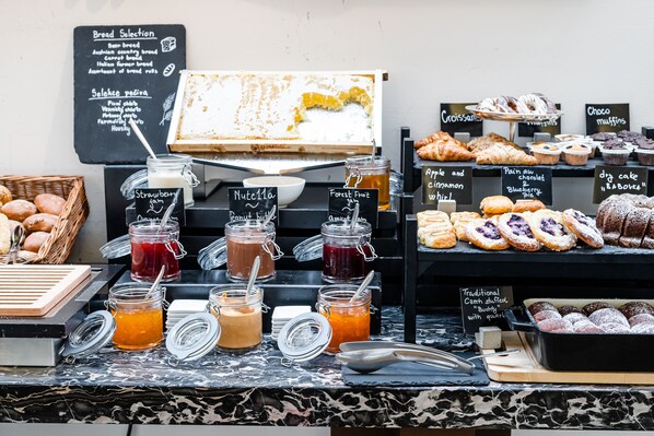 Mostrador de panadería con panes, pasteles y mermeladas.