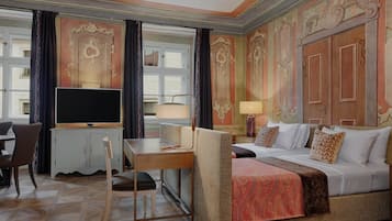 Una habitación de hotel con cama, escritorio, silla, televisor y ventana con cortinas.