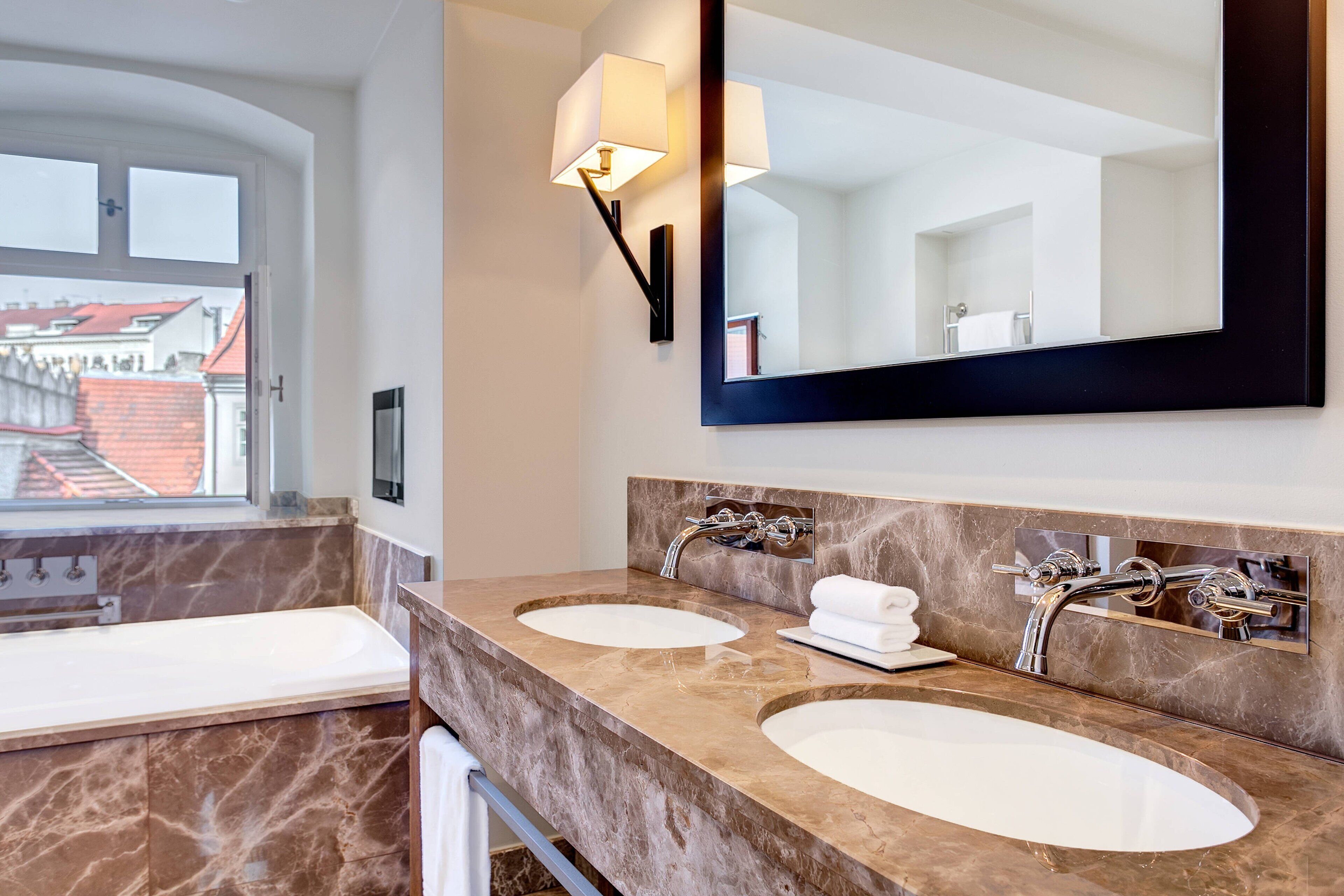 Ein modernes Badezimmer mit zwei Waschbecken, einem großen Spiegel und einem Fenster mit Blick nach draußen.
