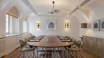 A conference room with a long table, chairs, and framed artwork on the walls.