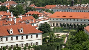 Un edificio histórico con tejados de tejas rojas, un patio central y una estatua.