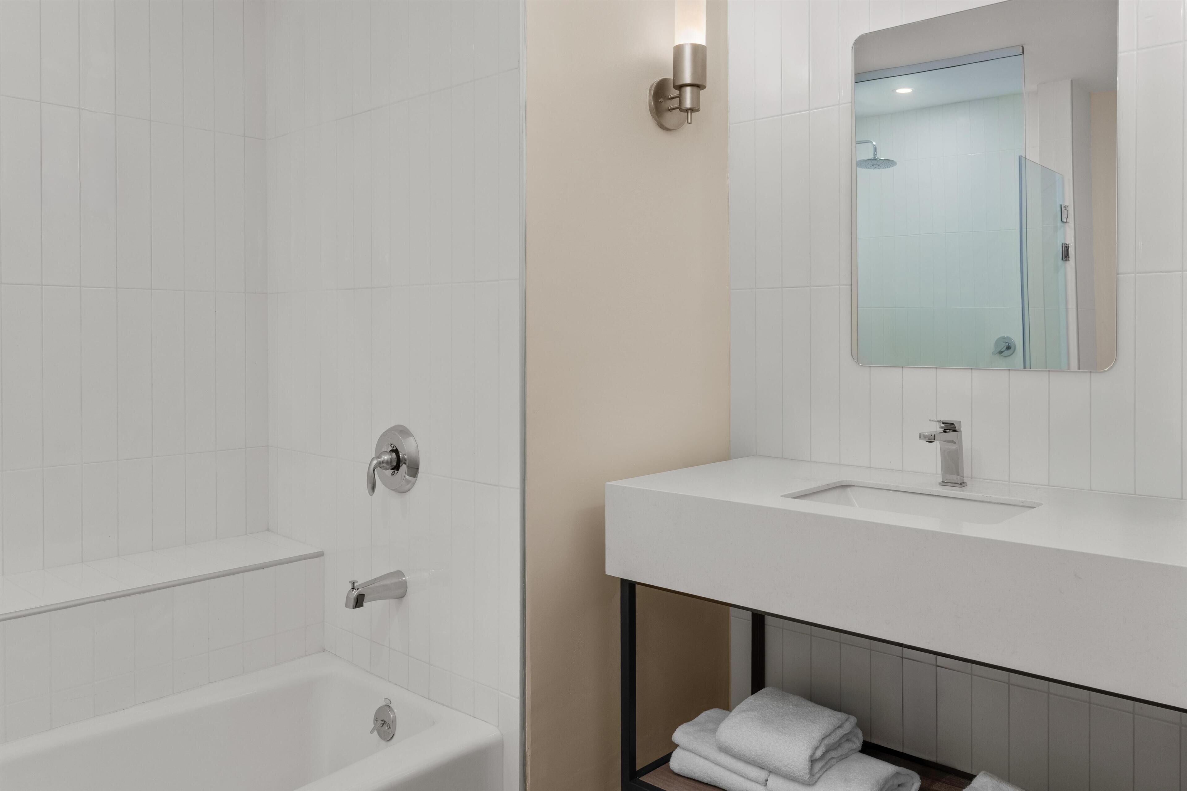 Un baño moderno con una bañera, un lavabo y un espejo.