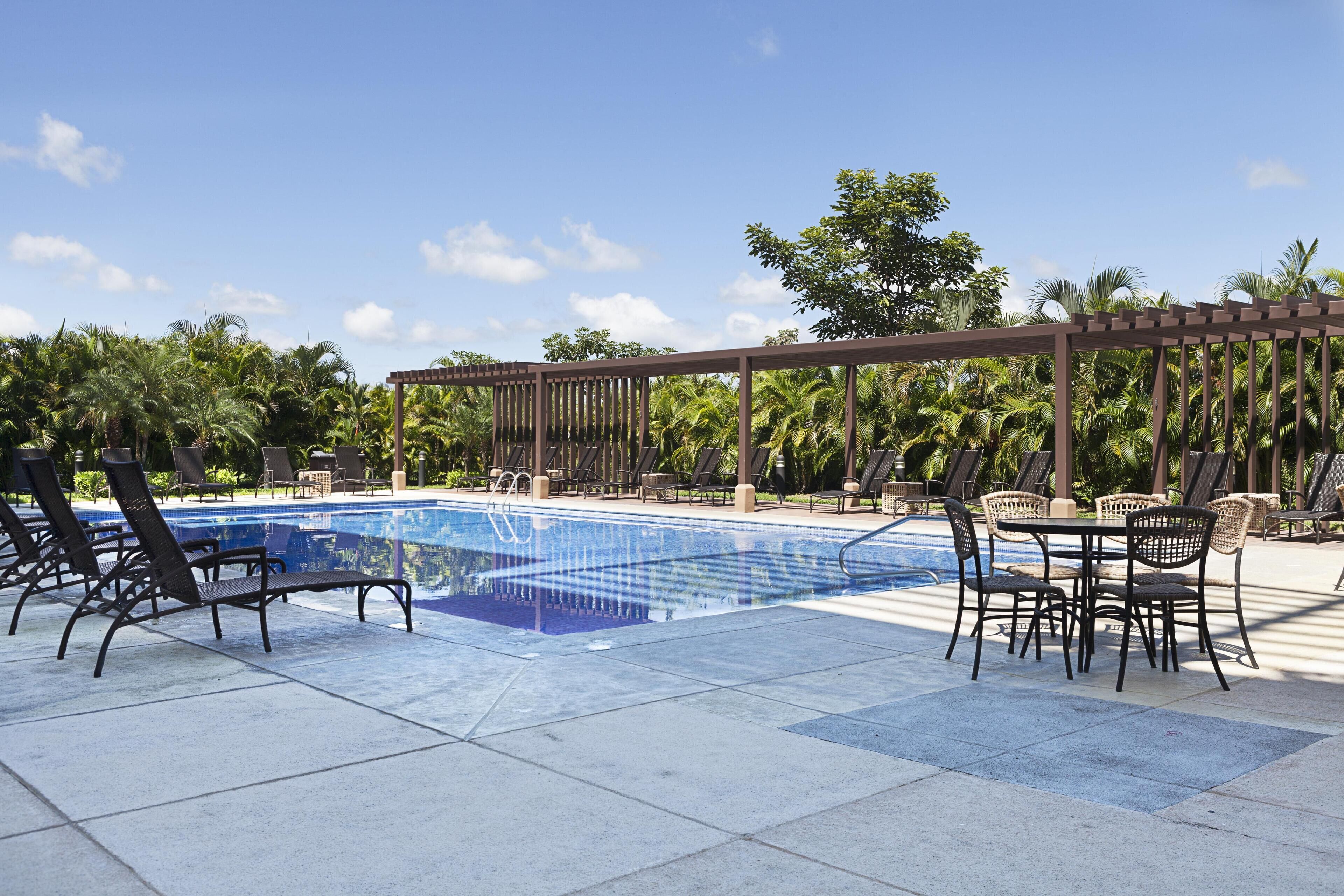 Un espace piscine avec des chaises longues et une pergola.