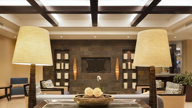 A lobby with a reception desk, two lamps, a stone wall, and a television.