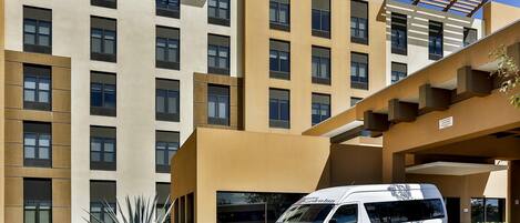 Un hotel Hilton Garden Inn con fachada moderna, una furgoneta estacionada al frente y un césped bien cuidado.