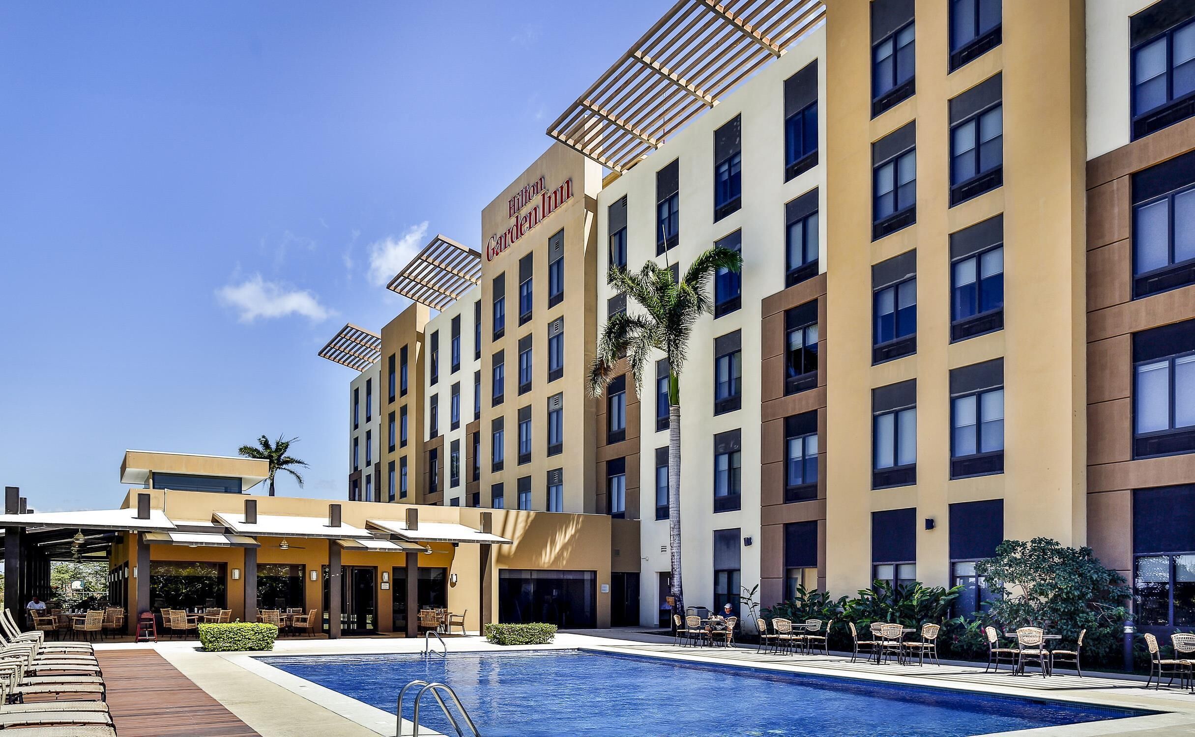 A hotel with a swimming pool, outdoor seating, and a garden area.