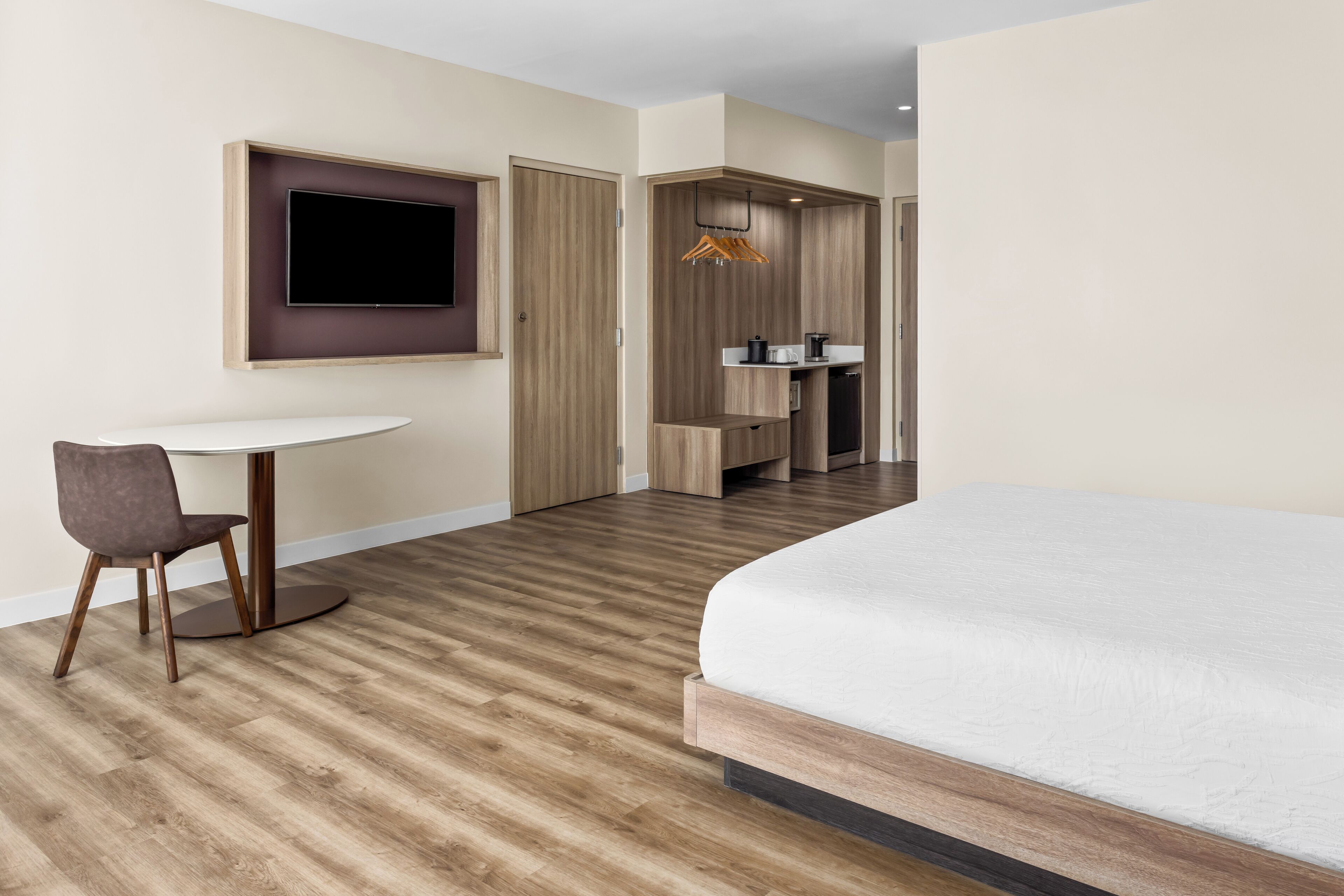 Une chambre d’hôtel équipée d’un lit, d’un bureau, d’une chaise, d’une télévision et d’une kitchenette.