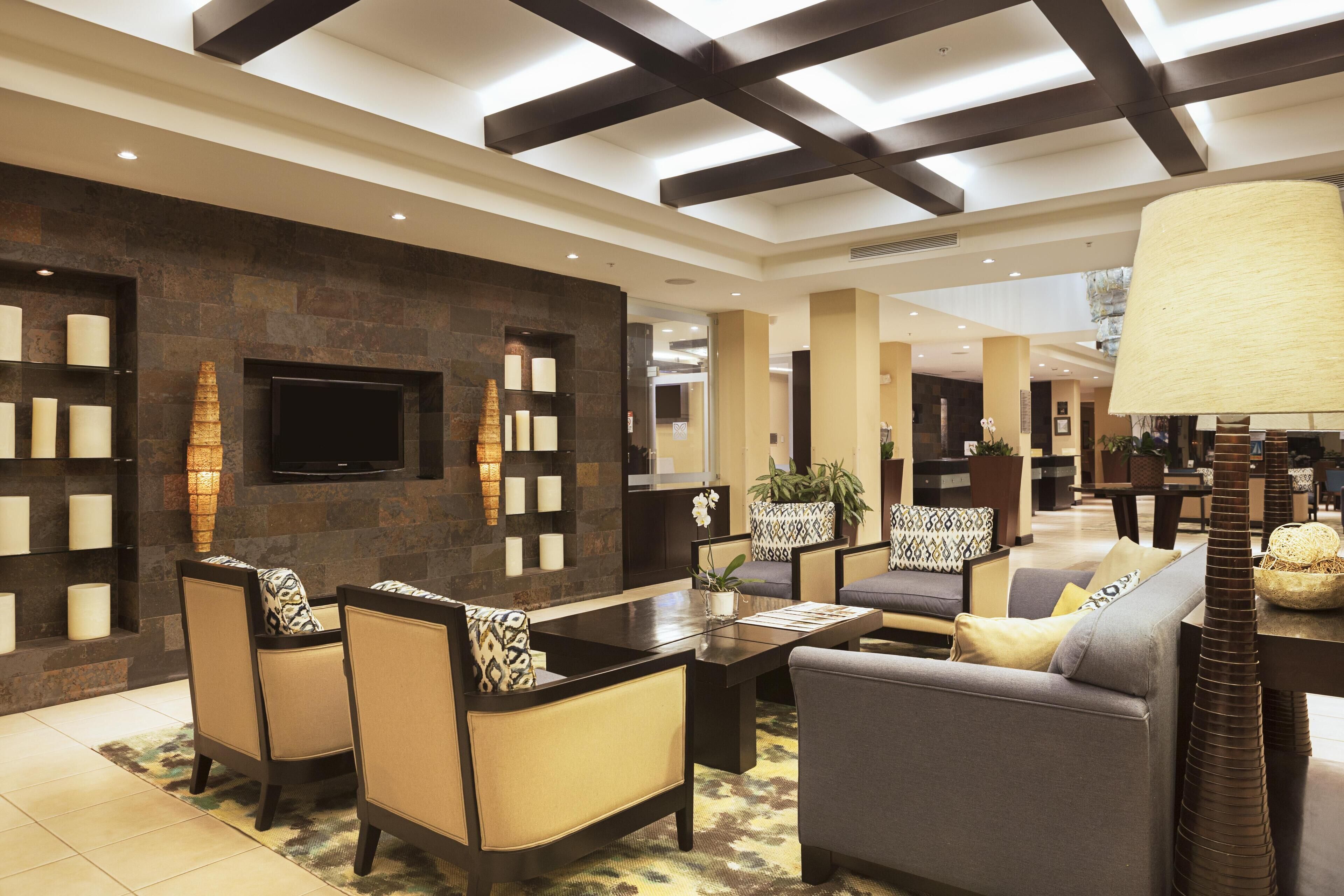 A modern lobby with a stone wall, a flat-screen TV, and a seating area with sofas and chairs.