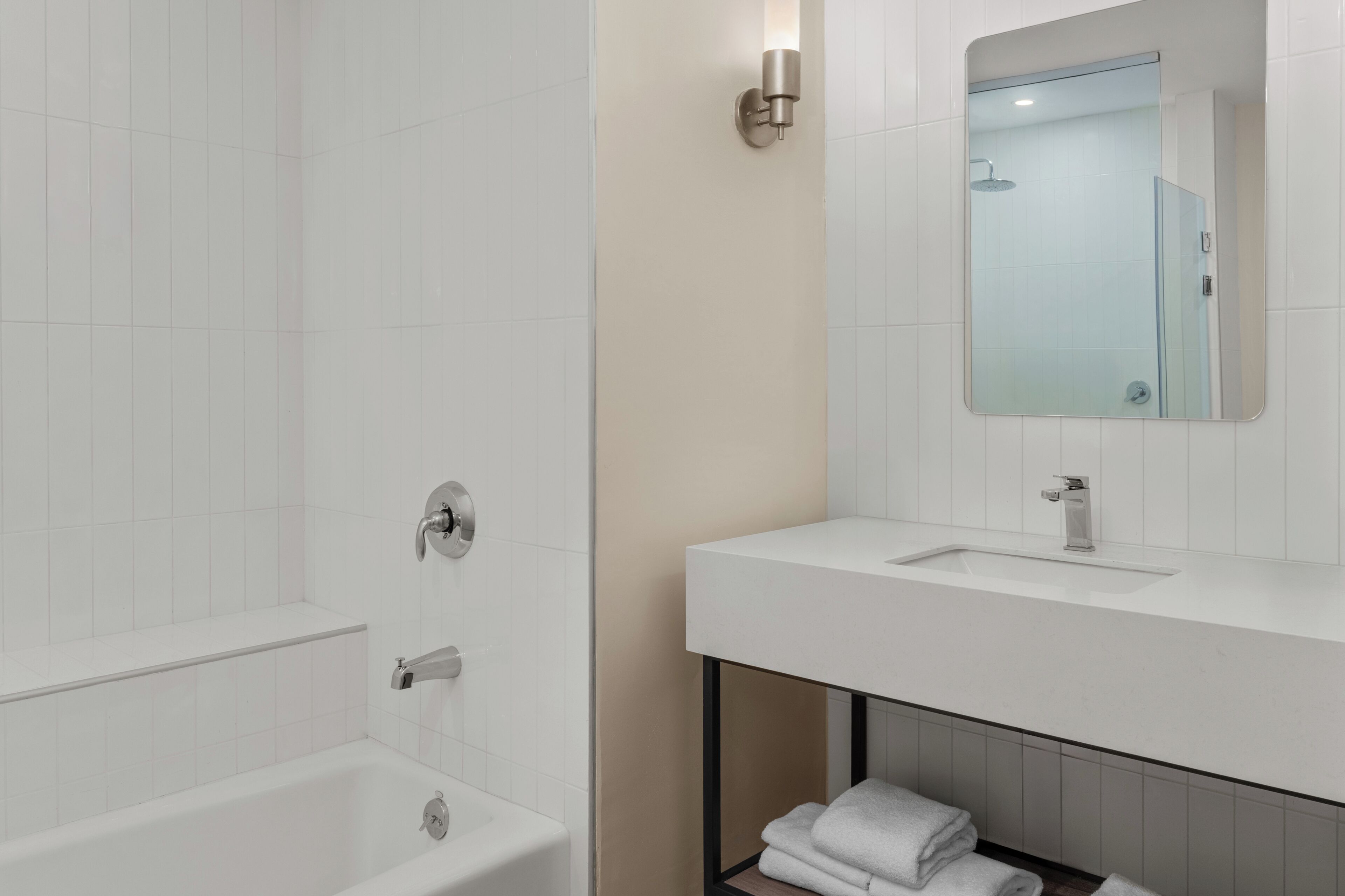 A modern bathroom with a bathtub, a sink, and a mirror.