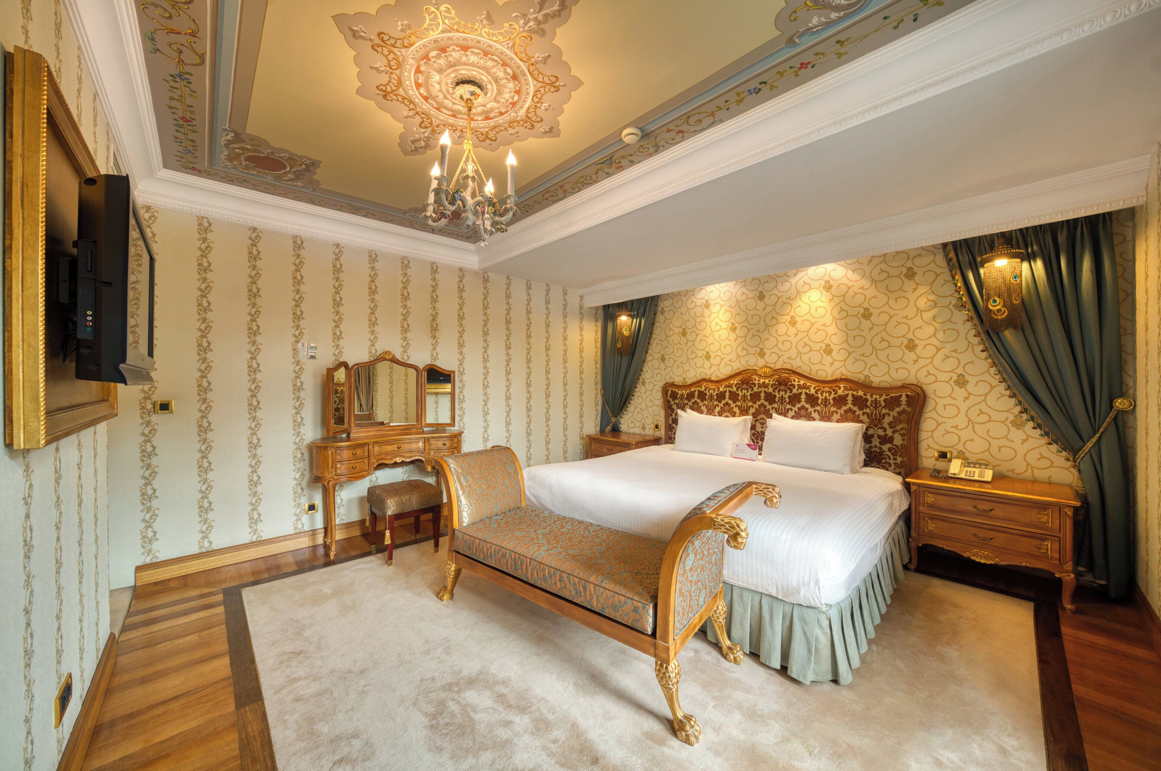 A luxurious bedroom with a large bed, ornate ceiling, and classic furniture.