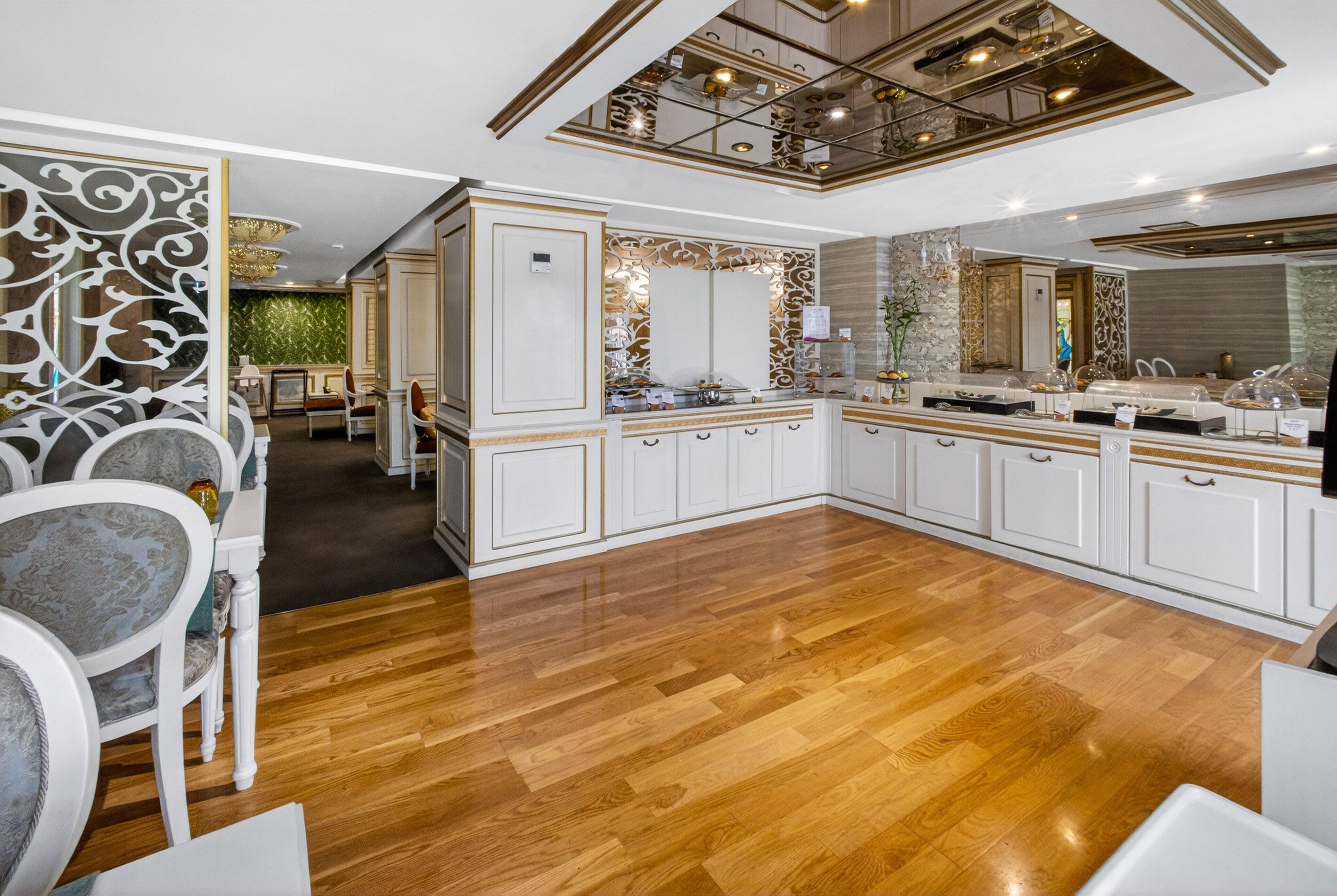 Una cocina amplia con armarios blancos, suelo de madera y techo decorativo.