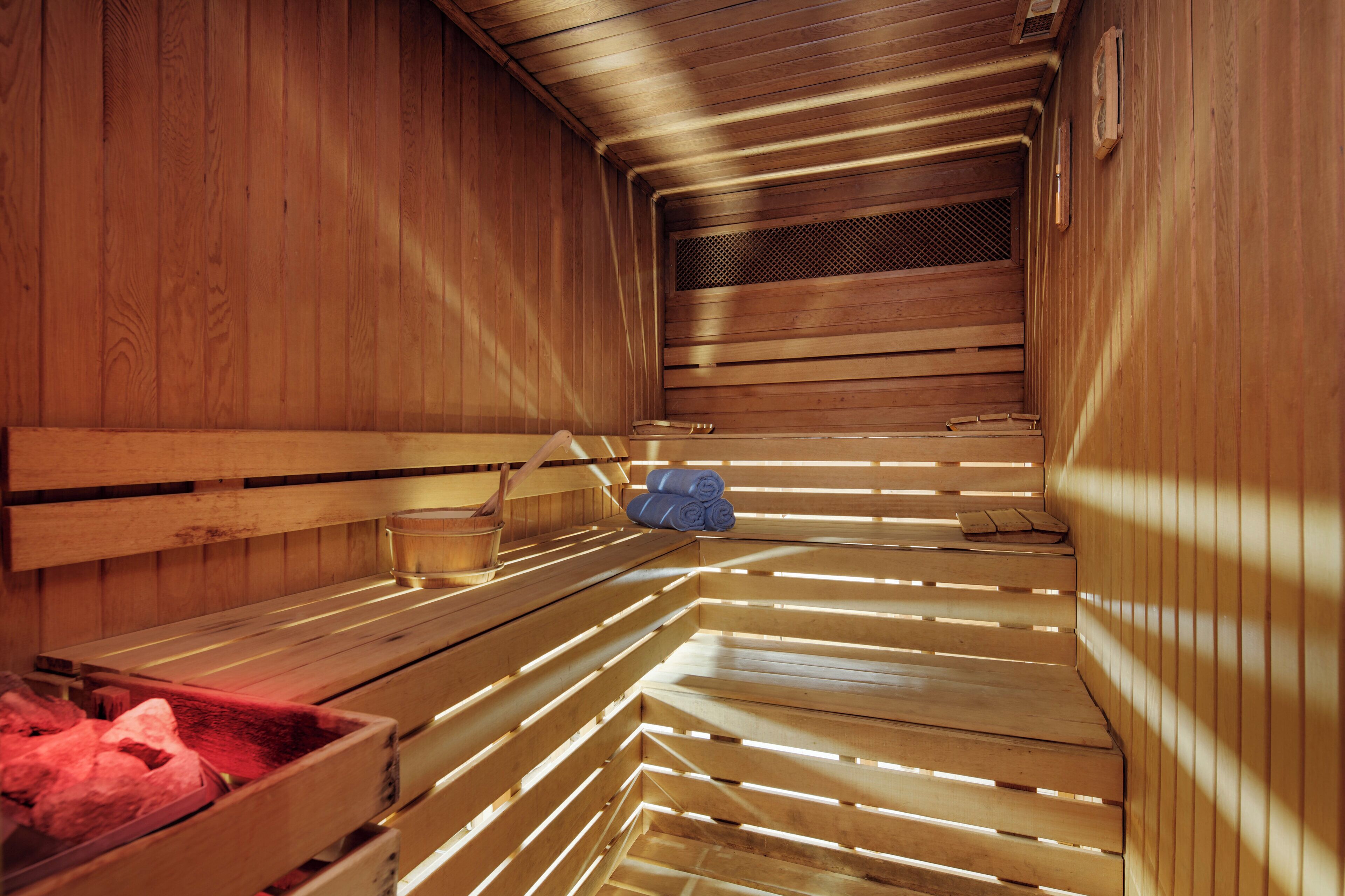 A sauna with wooden benches and a bench with a red towel.