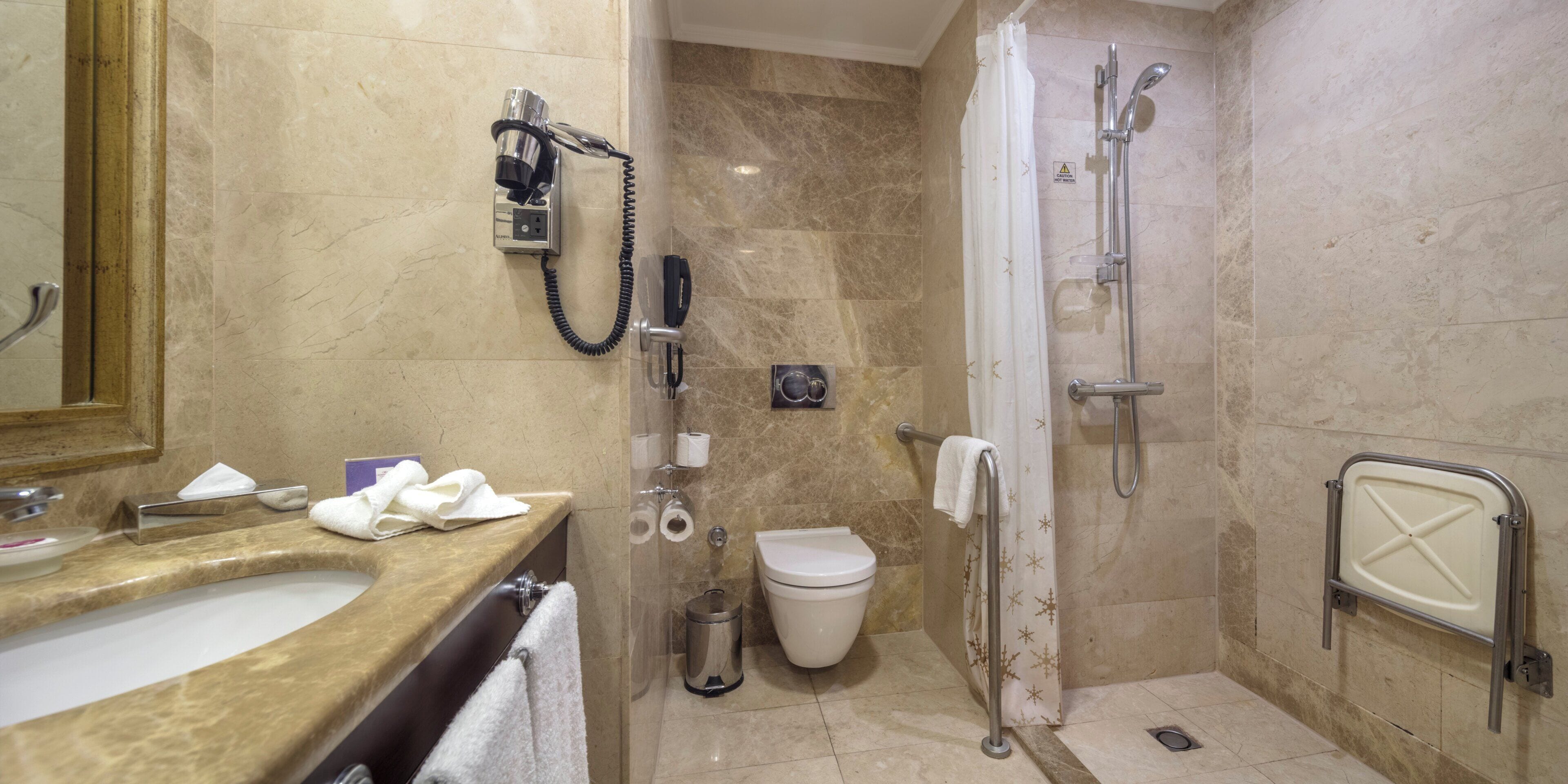 A bathroom with a sink, toilet, shower, and a hand dryer.